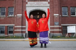 Kanahus and Mayuk Manuel, Secwepemc and Ktunaxa land defenders with the Tiny House Warriors, stand outside of the entrance of the former Kamloops Indian Residential School in Kamloops, B.C., Canada, on April 14, 2022. Several of their family members had attended the school, which includes their father, Arthur Manuel. (Photo by Aaron Hemens for HuffPost)