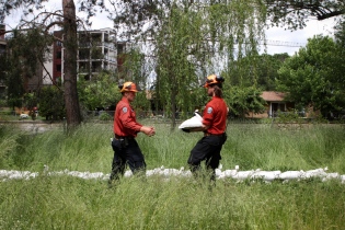 Members of BC Wildfire Service place sandbags in a backyard facing Mission Creek in Kelowna, B.C., on June 14, 2022. (Photo by Aaron Hemens for the Globe and Mail)
